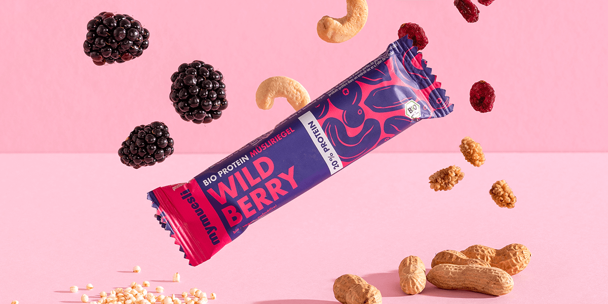 mymuesli Bio Protein Müsliriegel Wild Berry umgeben von frischen Maulbeeren, Cranberries, Knackige Reiscrispies, Cashewkerne und Mandeln
