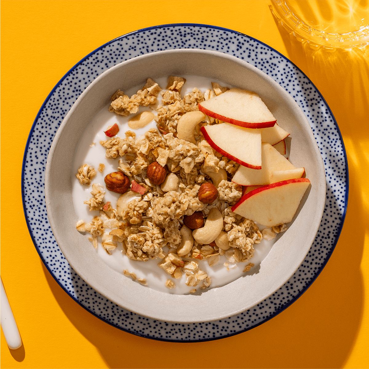 mymuesli Bio Low Sugar Roasted Nuts Müsli in Schale mit Joghurt und frischen Äpfeln