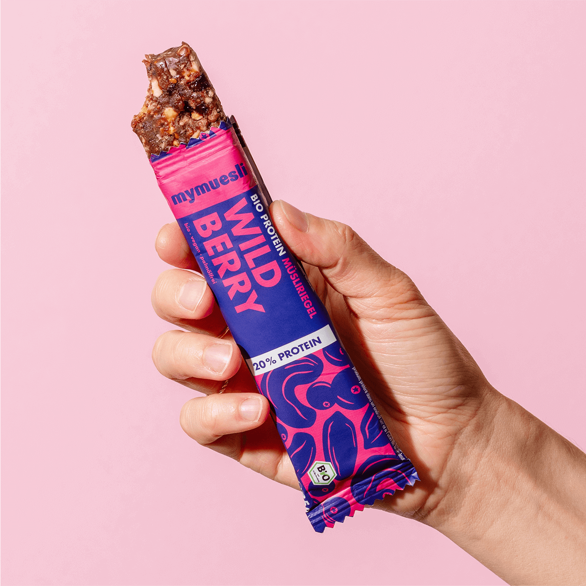 mymuesli Bio Protein Müsliriegel Wild Berry ausgepackt mit abgebissener Ecke.