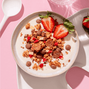 mymuesli Bio Strawberry Yoghurt Crunch in Schale mit Joghurt und frischen Erdbeeren