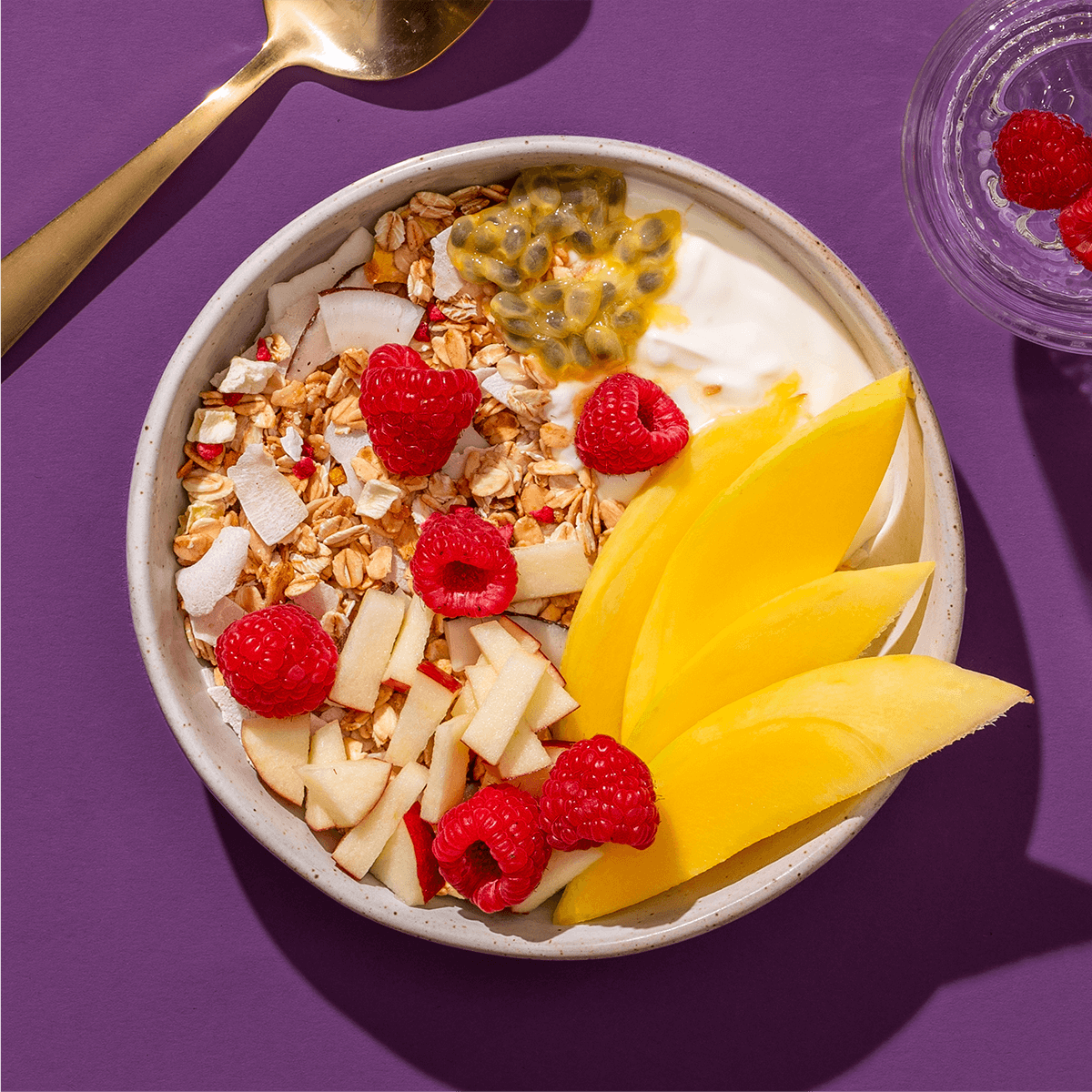 mymuesli Bio Mango Passionfruit Granola mit frischer Maracuja, Mango, Himbeeren und Apfel sowie Joghurt in Schale