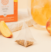 Tree of Tea Ice Tea Peach Beutel neben einem Stück Pfirsich
