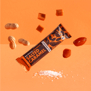 mymuesli Bio Protein Müsliriegel Salted Caramel umgeben von Datteln, Erdnüsse und Karamell Würfel.