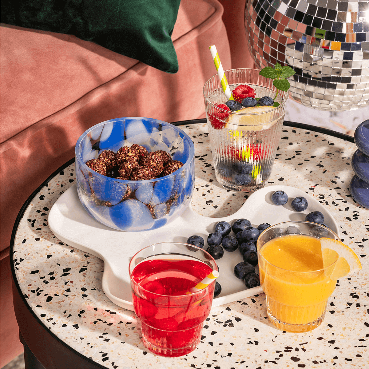 mymuesli Bio Raspberry Dark Choc Crunchy Bites in der Schüssel und schön angerichtet mit Beeren und Saft