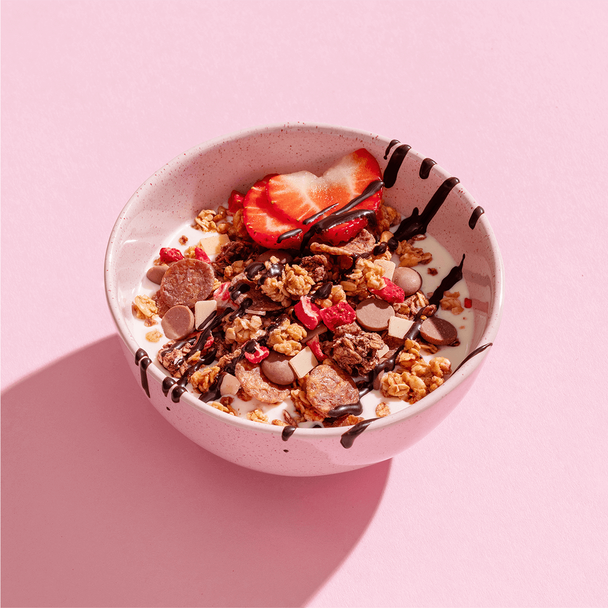 mymuesli Bio Strawberry Yoghurt Crunch in Schale mit Joghurt, frischen Erdbeeren und Schoko-Sauce