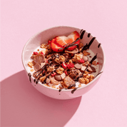 mymuesli Bio Strawberry Yoghurt Crunch in Schale mit Joghurt, frischen Erdbeeren und Schoko-Sauce