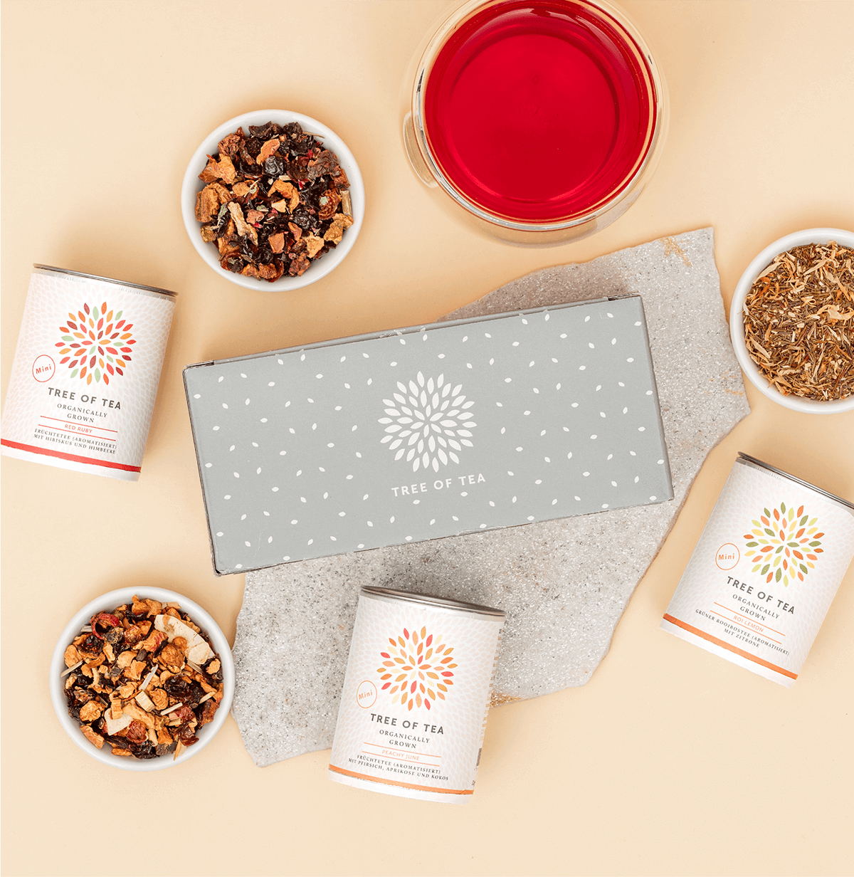 Tree of Tea 3er Mini Früchtetee Set liegend mit einer Tasse Tee daneben