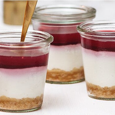 Cheesecake im Glas mit Tee-Topping und goldenem Löffel
