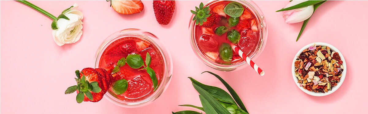 Erdbeer Rhabarber Cocktail mit einem Strohhalm und Tee daneben