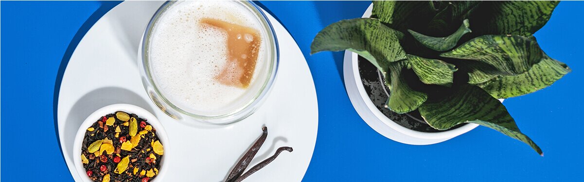 Iced Chai Latte mit einem Schälchen Tee daneben