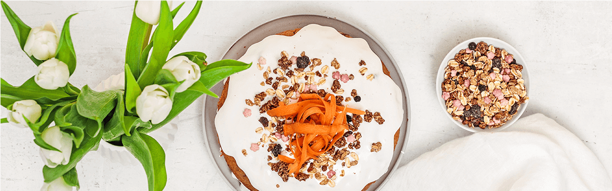 Naked Carrot Cake auf einem Teller, mit geraspelter Möhre dekoriert