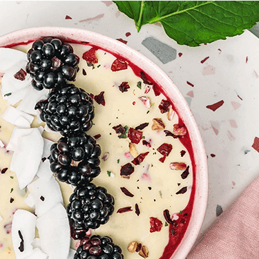 Magic Shell Smoothie Bowl mit Beeren und Kokoschips dekoriert