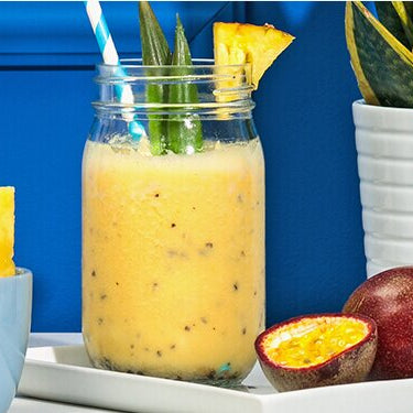 Ananas Passionsfrucht Smoothie mit einer Passionsfrucht und Ananas daneben