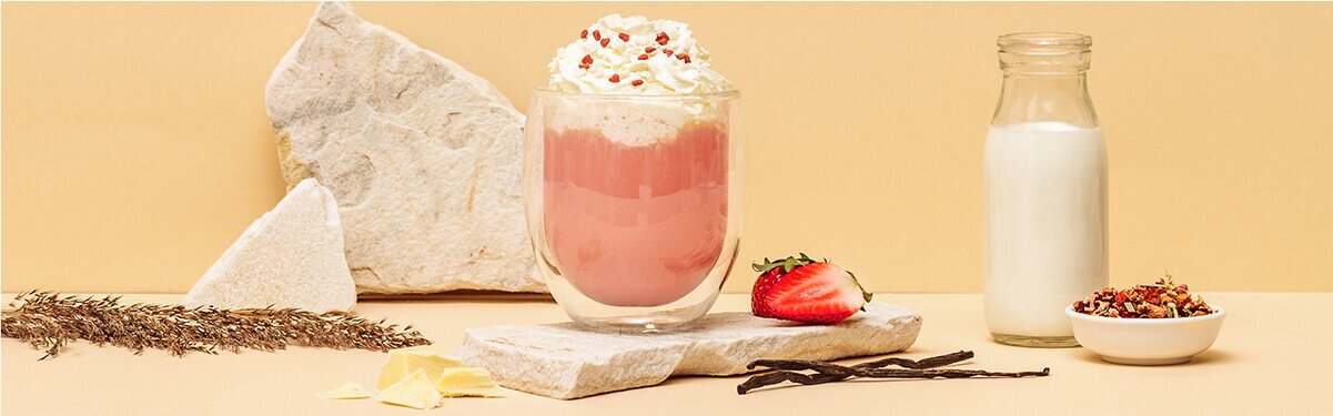 Pink Hot Chocolate mit Sahne und Erdbeeren daneben