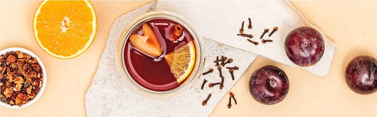 Pflaumen Punsch mit Orangen, Nelken und Tee daneben