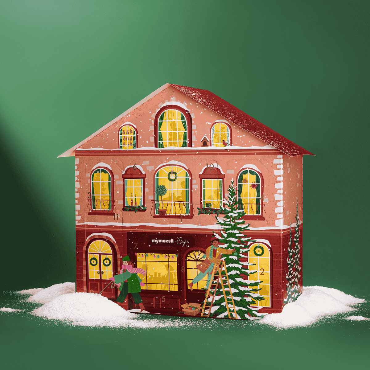 Rotes Adventskalenderhaus mit leichtem Schnee. Vor dem Haus läuft eine Frau mit ihrem Dackel vorbei. Ein Mann steht auf der Leiter und schmückt einen Tannenbaum. Die Fenster des Hauses sind beleuchtet. 