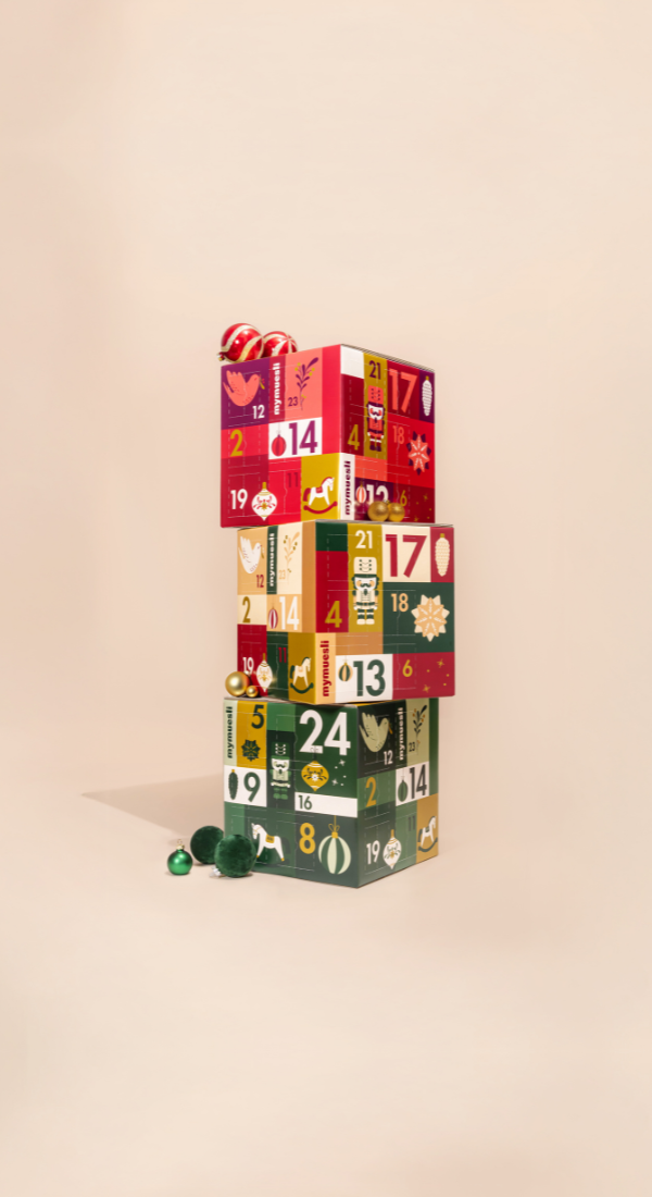 mymuesli Bio Müesli und Porridge Adventskalender, getragen von einer Frau in weihnachtlich grünem Hintergrund.