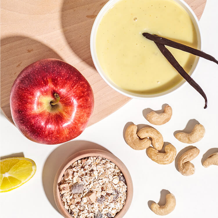 Vanillesauce, ein Apfel, Cashews und Müsli