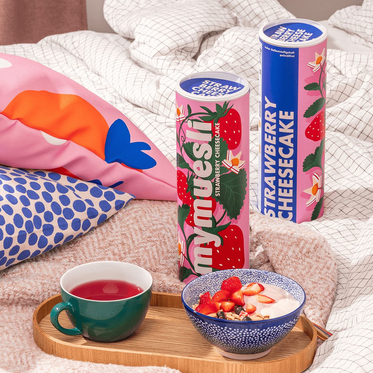 mymuesli Bio Strawberry Cheesecake Müsli auf Tablett mit Tee im Bett mit Müslidosen