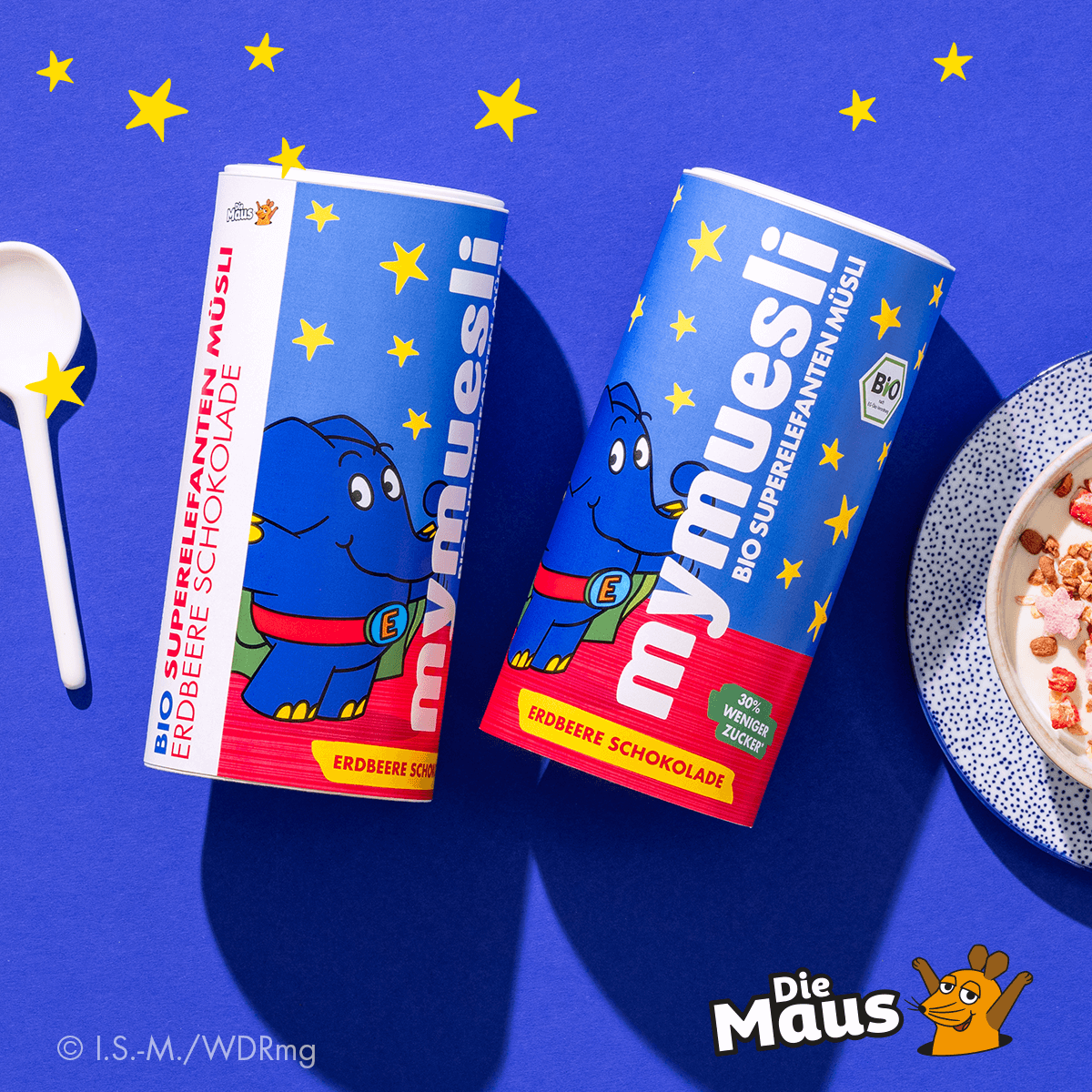 mymuesli Bio Superelefanten Müsli Dose von Vorne und der Seite neben Schüssel mit Müsli und Joghurt