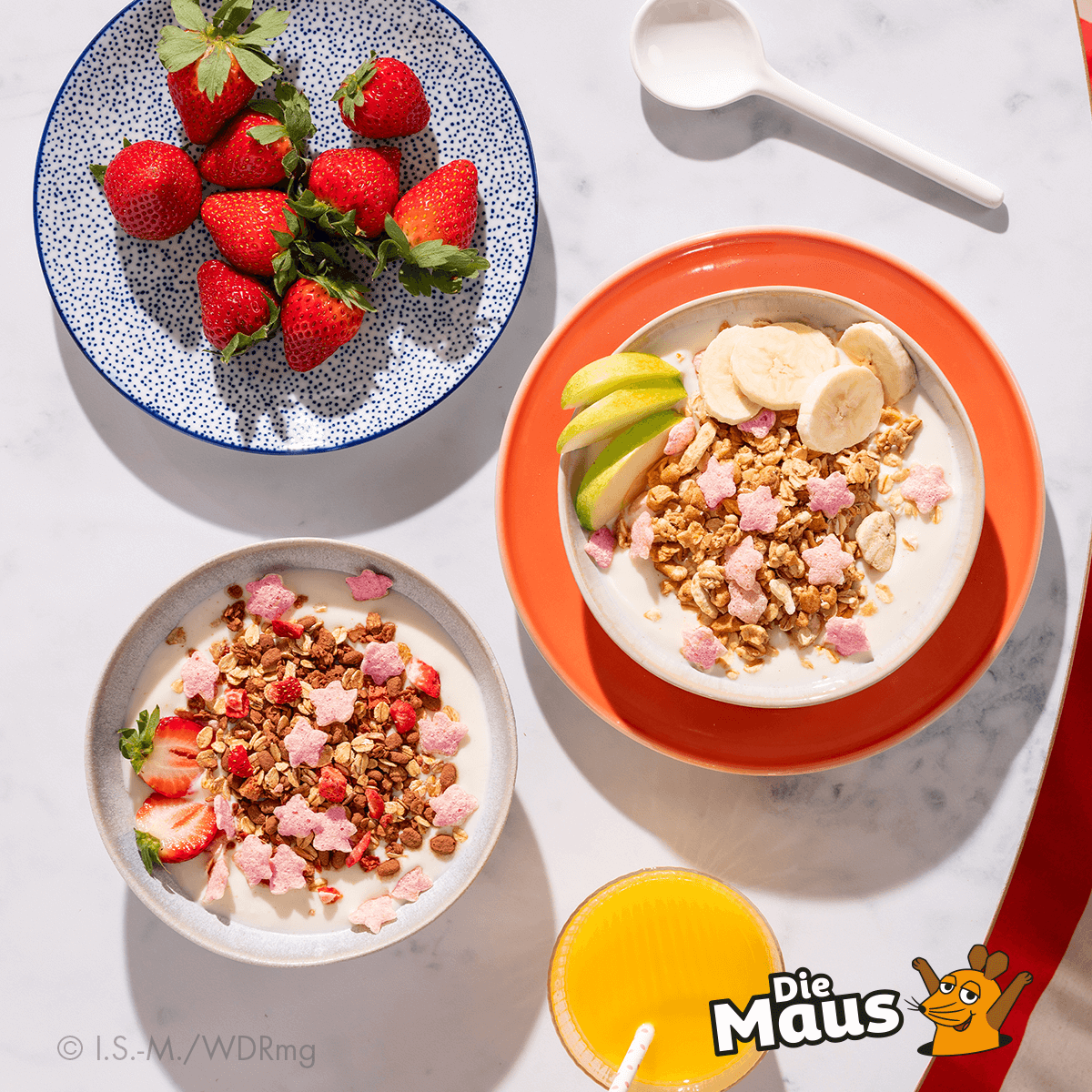 mymuesli Bio Supermaus und Superelefanten Müslis zubereitet neben Teller mit frischen Erdbeeren