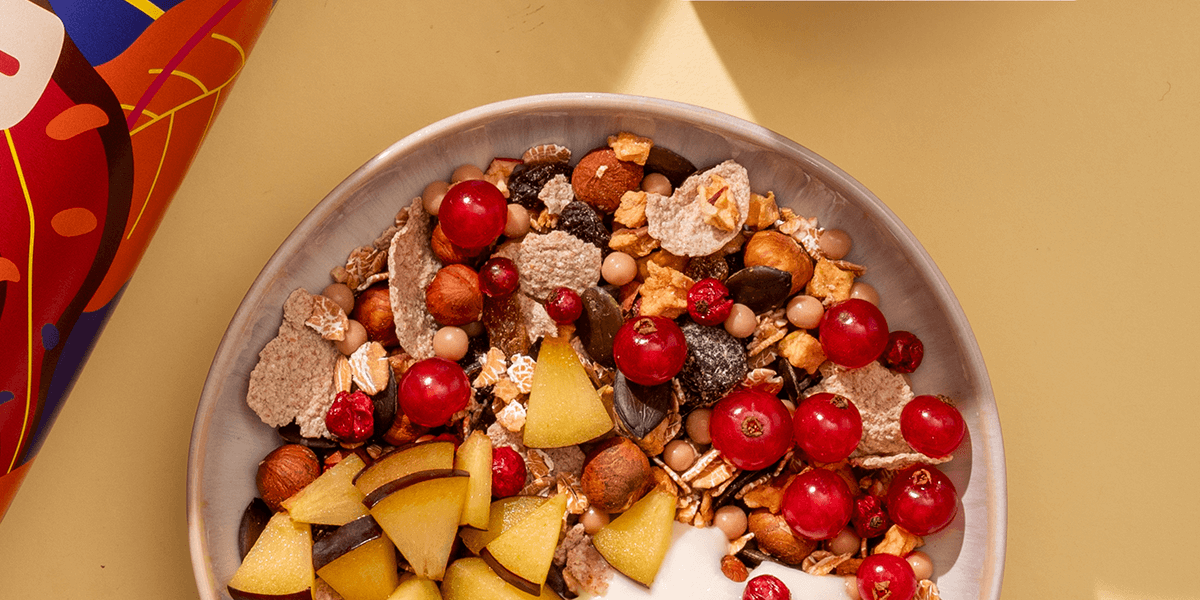 Eine Schüssel mymuesli Herbst-Müsli mit Johannisbeeren, Pflaumenstücken und Joghurt