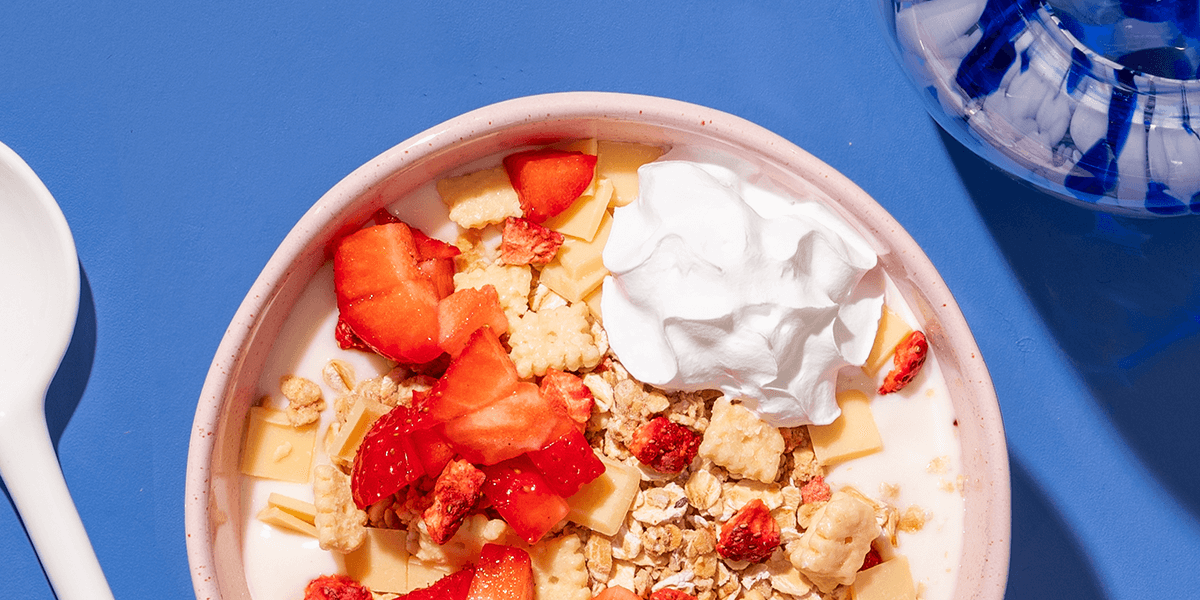 mymuesli Bio Strawberry Cheesecake Müsli in Schale mit frischen Erdbeeren und Sahne