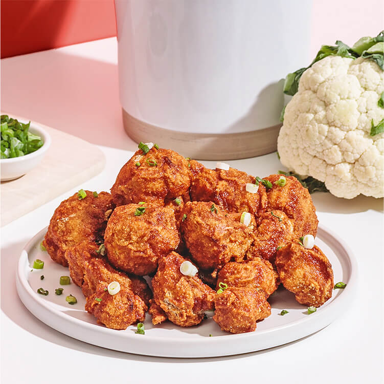 Cauliflower Buffalo Wings auf einem Teller mit Lauchzwiebeln dekoriert