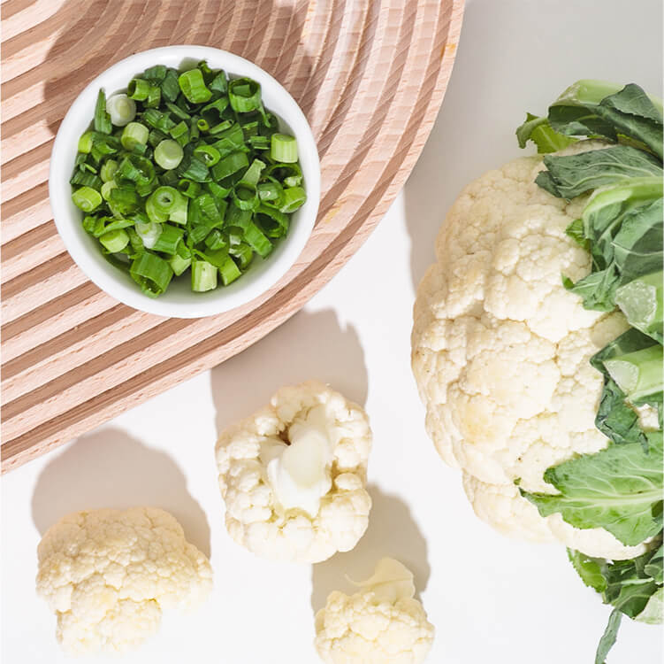 Eine Schale Lauchzwiebeln und Blumenkohl daneben