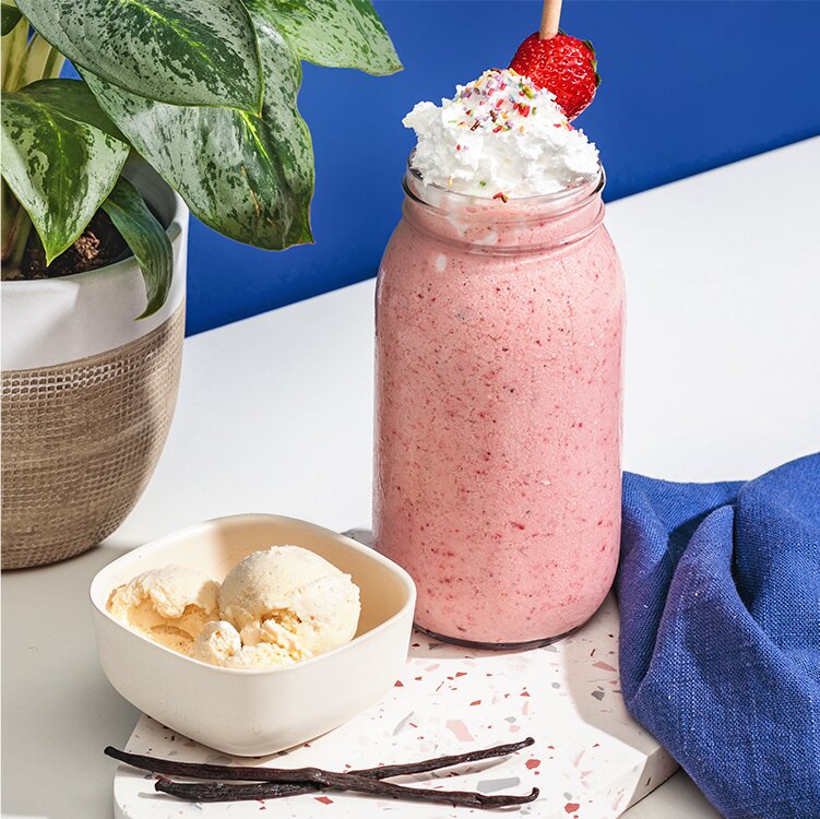 Erdbeer Haferdrinkshake mit Sahne und einer Schale Eis daneben