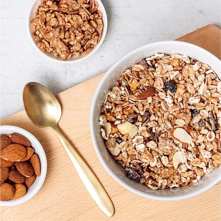 Müsli in einer Schale mit Nüssen und einem goldenen Löffel daneben