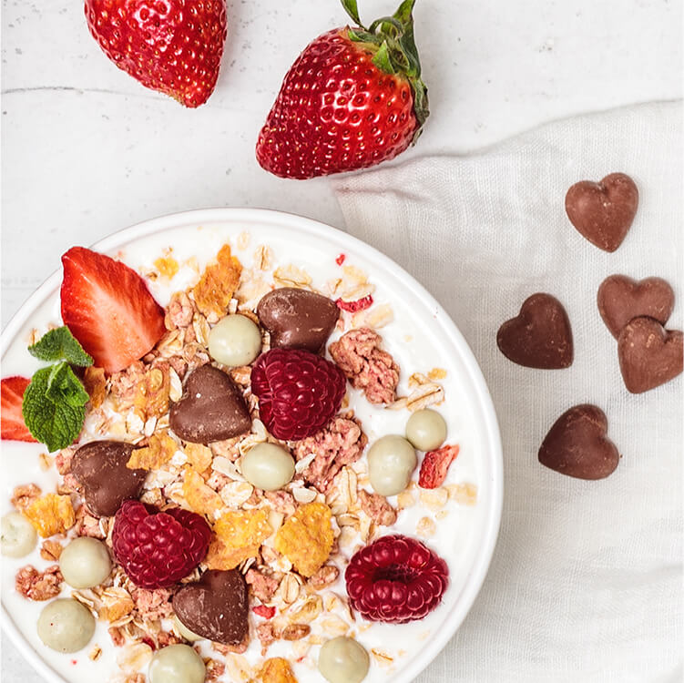 Ein Teller mit Schokoherzen, Himbeeren, Erdbeeren und Müsli