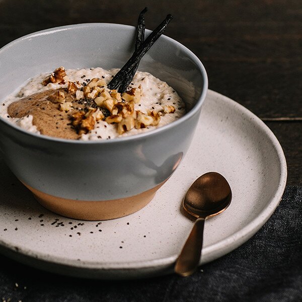 Porridge mit Chiasamen in einer Schüssel, dekoriert mit Vanilleschoten und Walnüssen