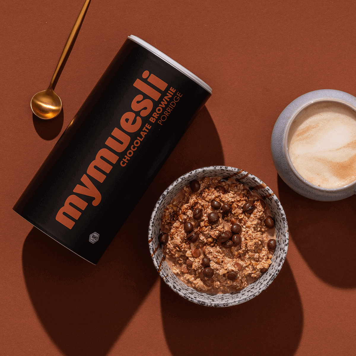 mymuesli Bio Porridge Chocolate Brownie Dose neben Porridge in Schale und Kaffee