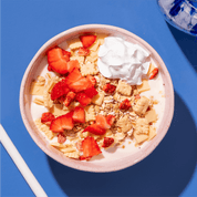 mymuesli Bio Strawberry Cheesecake Müsli in Schale mit frischen Erdbeeren, Milch und Sahne