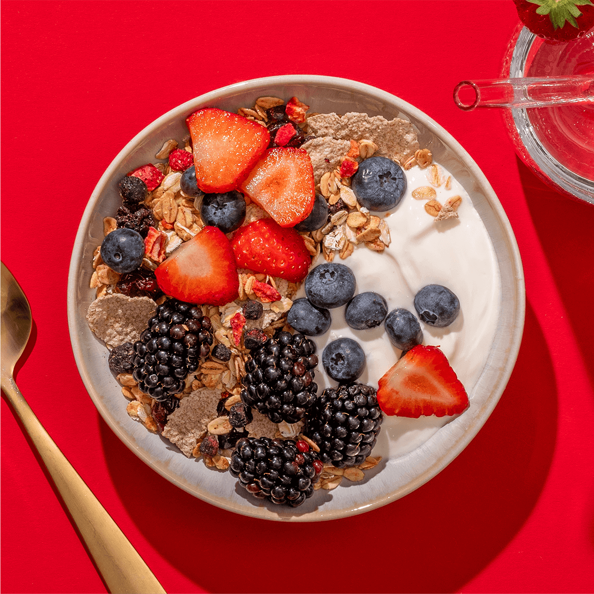 mymuesli Bio Blackberry Granola in Schale mit frischen Erdbeeren, Blaubeeren, Brombeeren und Joghurt