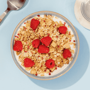 mymuesli Bio Low Sugar Yoghurt Raspberry Crunch in Schale mit Joghurt und frischen Himbeeren