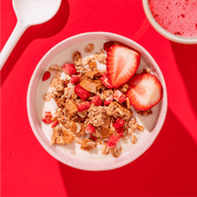 mymuesli Bio Pink Strawberry Crunchy in Schüssel mit Joghurt und frischen Erdbeeren serviert mit Erdbeer Smoothie