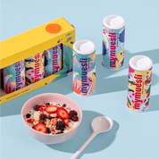 mymuesli Bio Sommer Minis neben Schale mit Sommer Müsli mit Milch und frischen Erdbeeren