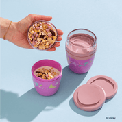 Zwei Disney Princess Mini 2Go Becher, einer leer, der andere wird mit Joghurt und Müsli gefüllt