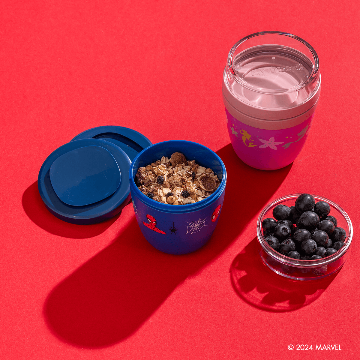 Spider-Man Mini 2Go Becher wird mit Heidelbeeren und Müsli gefüllt und daneben ein leerer Princess Mini 2Go Becher