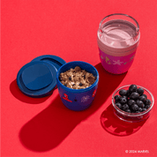 Spider-Man Mini 2Go Becher wird mit Heidelbeeren und Müsli gefüllt und daneben ein leerer Princess Mini 2Go Becher
