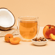 Tree of Tea Bio Peachy June in einem Glas Tee, mit Pfirsichen und einer halben Kokosnuss