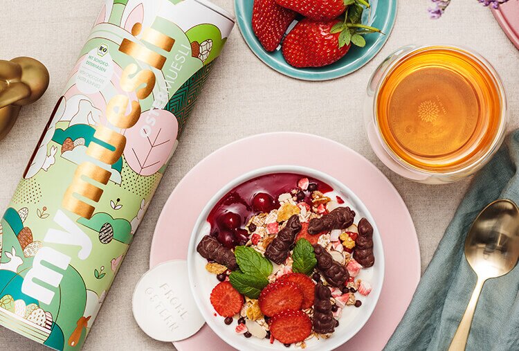 gedeckter Osterfruehstueckstisch mit mymuesli Oster Muesli Mueslischale mit Schokohasen und frischen Erdbeeren